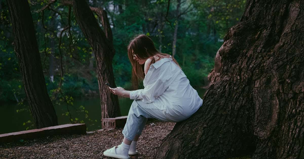 a-girl-sitting-on-a-tree-trunk-with-a-cell-phone-in-her-hands